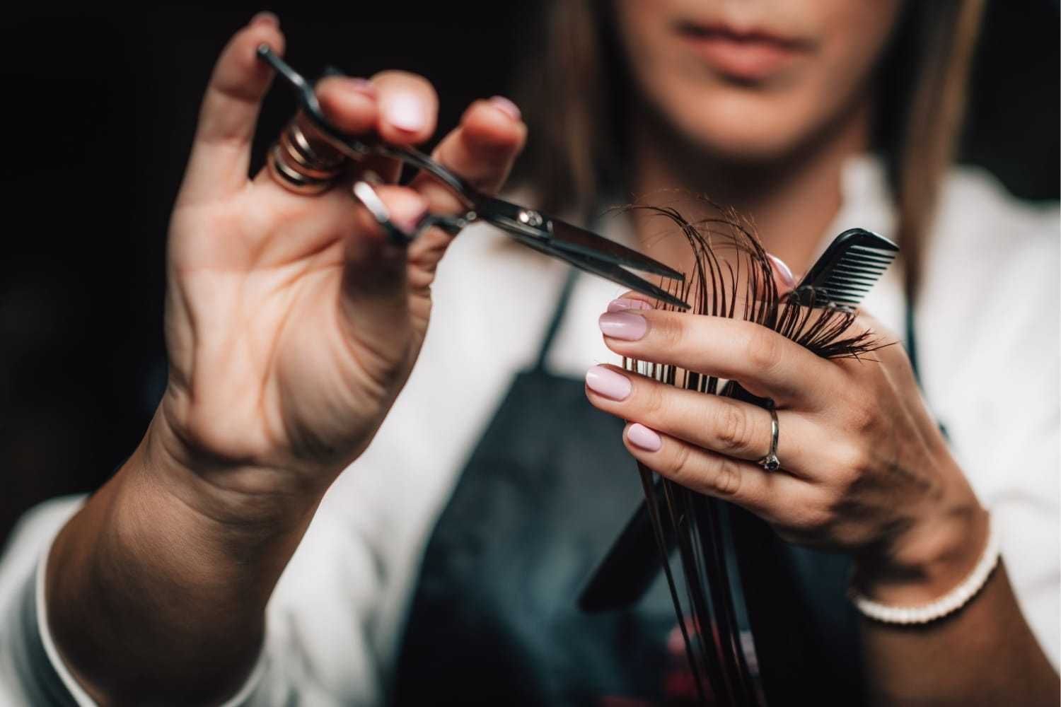 Hairdresser precisely trims hair with scissors and comb, focusing on detail and skill.